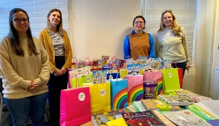 Four women standing behind lots of small colourful bags full of arts and crafts