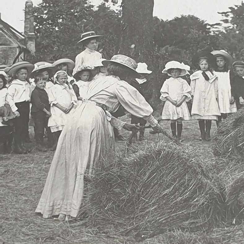 Eliza Chattaway demonstrating haymaking to a group of schoolchildren. 