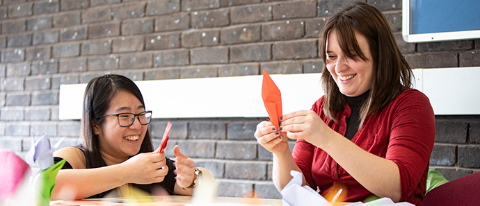 Students laughing and folding origami.