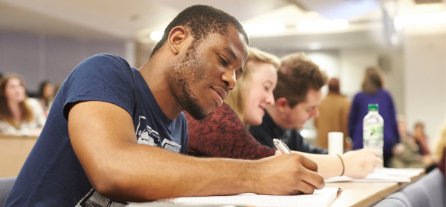 A master's student takes notes in a lecture theatre