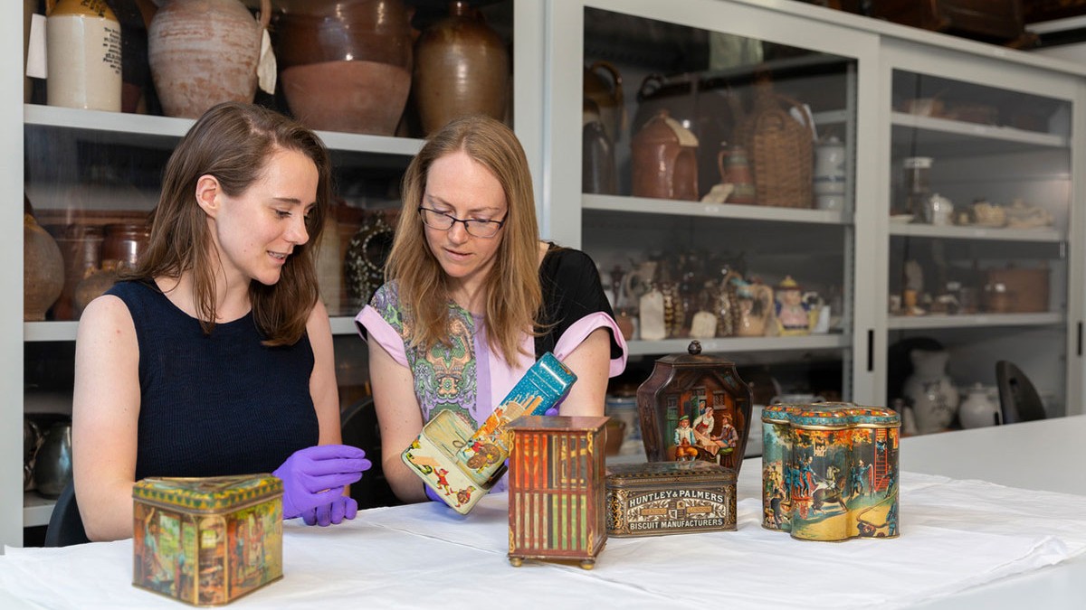 2 women sat examining artefact