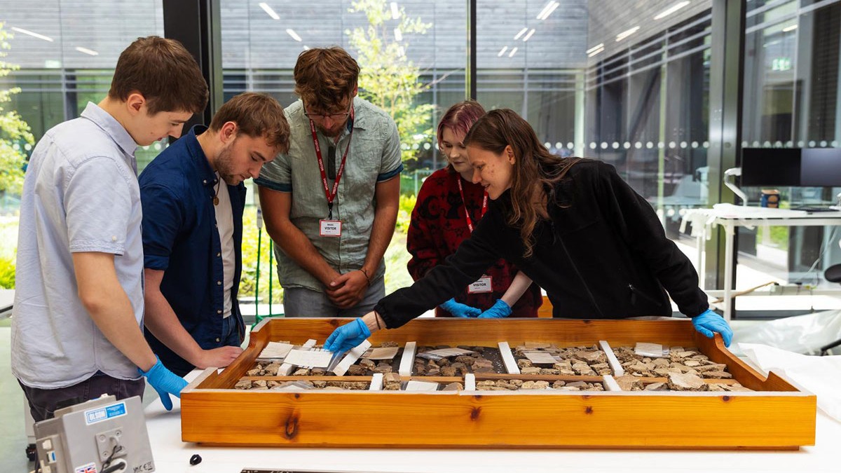 5 students looking at artefacts around a table