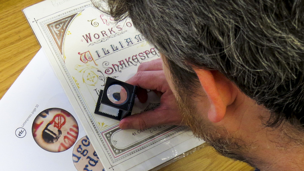 Close up of academic examining student design work with magnifying glass